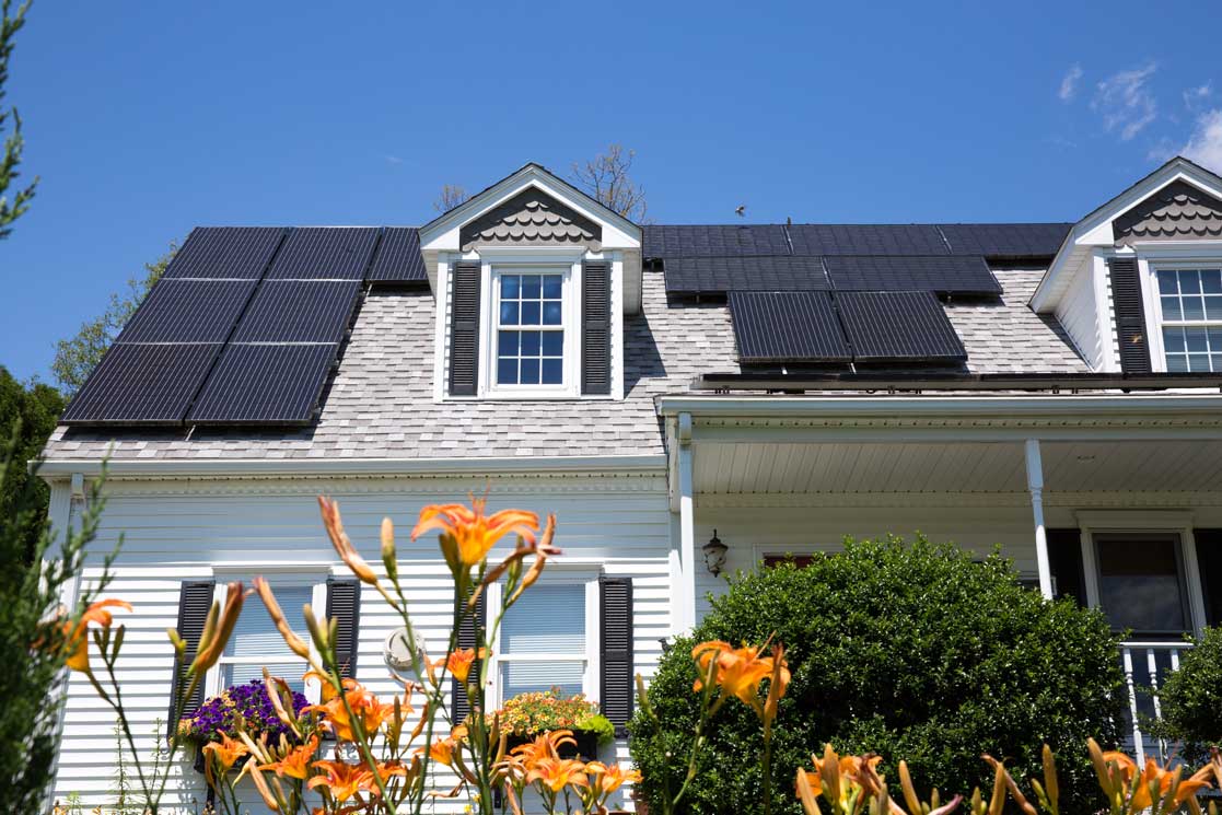 Solar panel installation on a nice cape cod house with sunny blue skies in the background